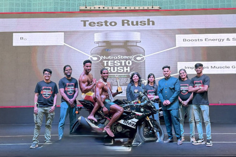 Group of people on a stage with a motorcycle, posing for a photo in front of a large screen displaying 'Testo Rush'.